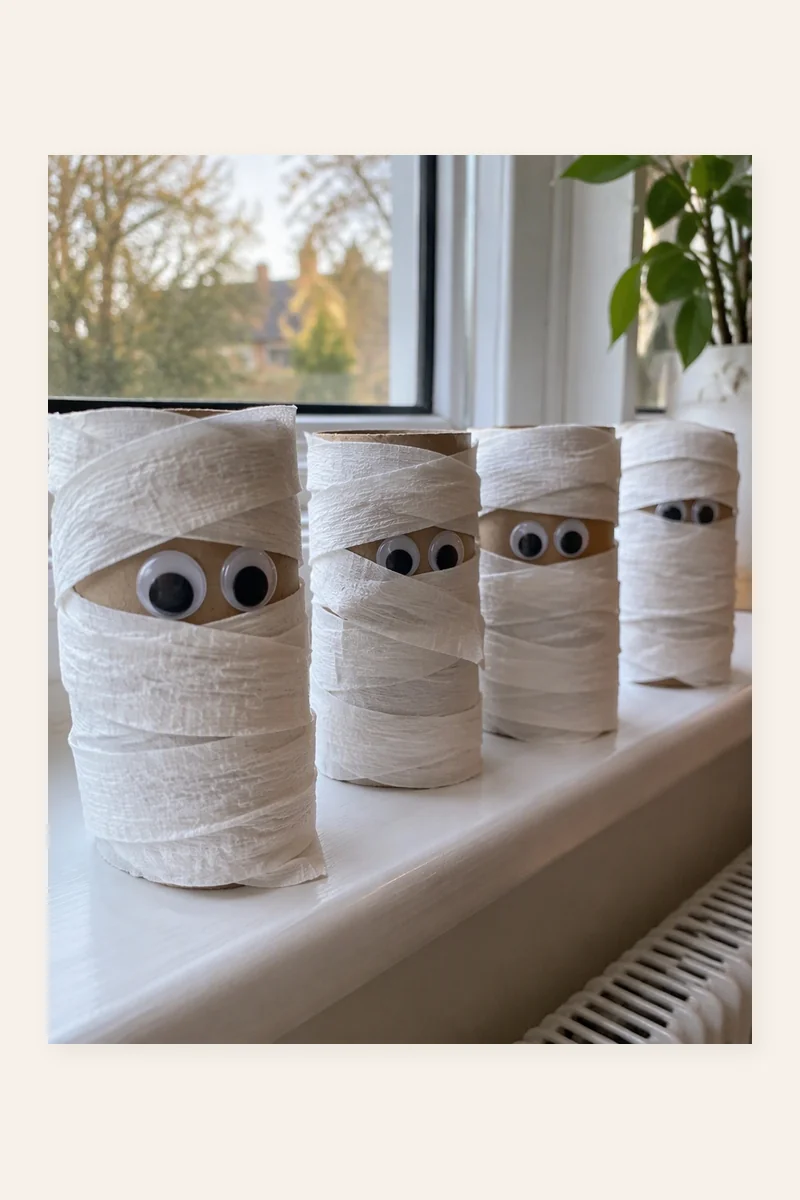 Toilet Roll Mummies craft with wrapped toilet rolls and googly eyes lined up on a windowsill